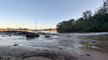 Betts Park beach, close up of the incoming tides with boats floating on the river in the background.
