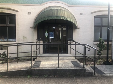 Photo shows the front entrance to Fairland Hall. The foreground of the image shows the accessibility ramp coming from the left of frame and the two steps are to the